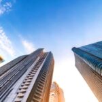 高層ビルを下から見上げたアングルの都市風景、青空と雲が広がる