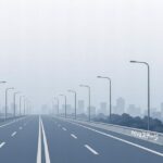 霧がかった都市風景を背景にした広い高速道路の正面ビュー。道路脇には「novaステージ」の表示がある。