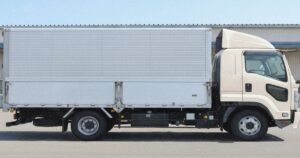 白い箱型トラックの側面写真、駐車場で停車している様子