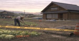 立ち入り禁止テープが張られた農地で作物を収穫する農家の様子